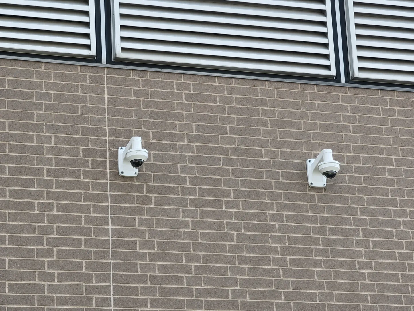 Dual exterior surveillance cameras installed on a commercial brick building